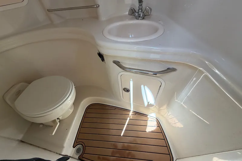 Slide: The Image of 2006 Sea Ray 300 Sundancer bathroom with toilet, sink, and wooden floor. - 60