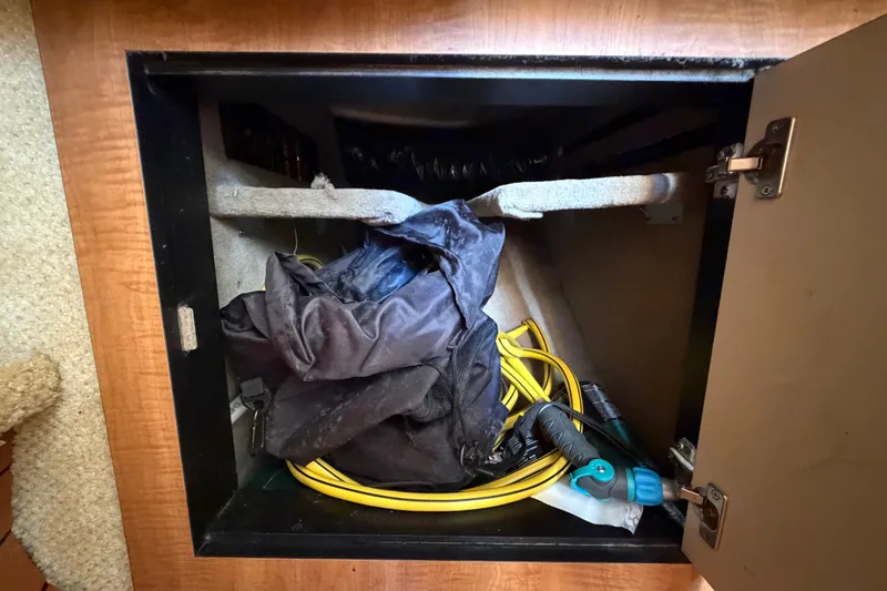Slide: The Image of Storage compartment in a 2006 Sea Ray 300 Sundancer with hose and black fabric. - 78
