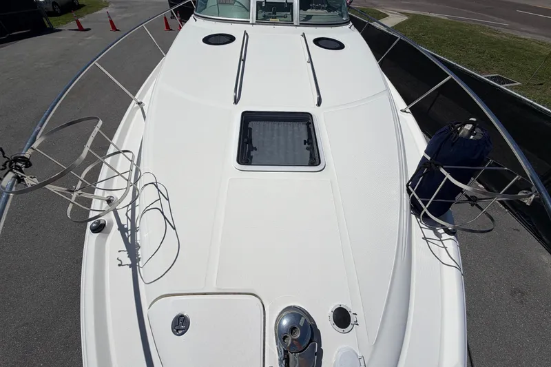 Slide: The Image of 2006 Sea Ray 300 Sundancer boat deck with railing and hatch, docked on pavement. - 51