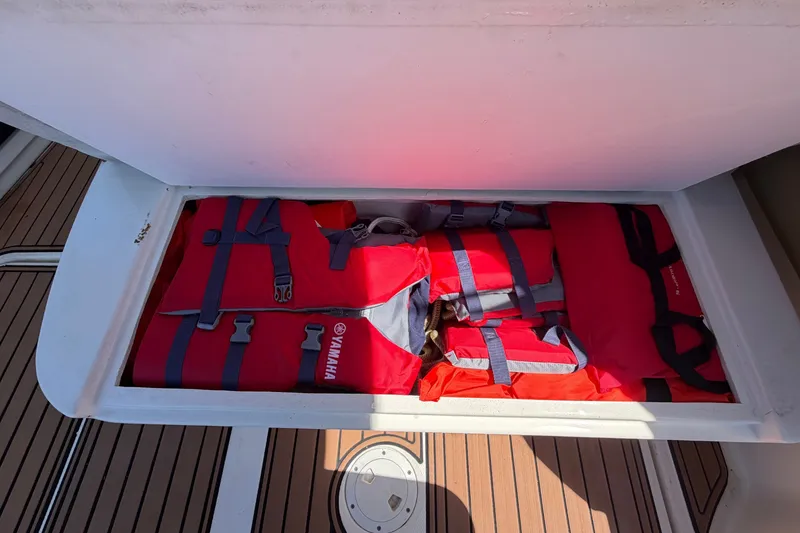 Slide: The Image of An open storage compartment on a boat reveals several red life jackets. - 21