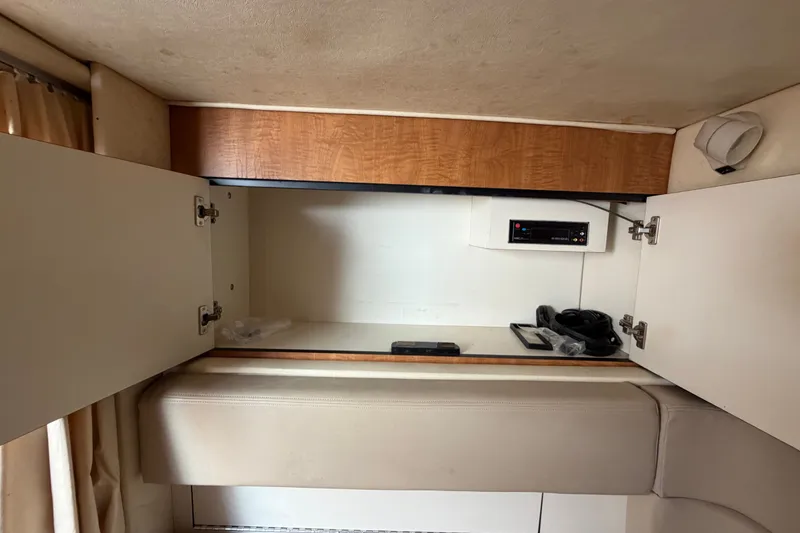 Slide: The Image of Open cabinet in 2006 Sea Ray 300 Sundancer boat interior, showing storage space and electronic equipment. - 101