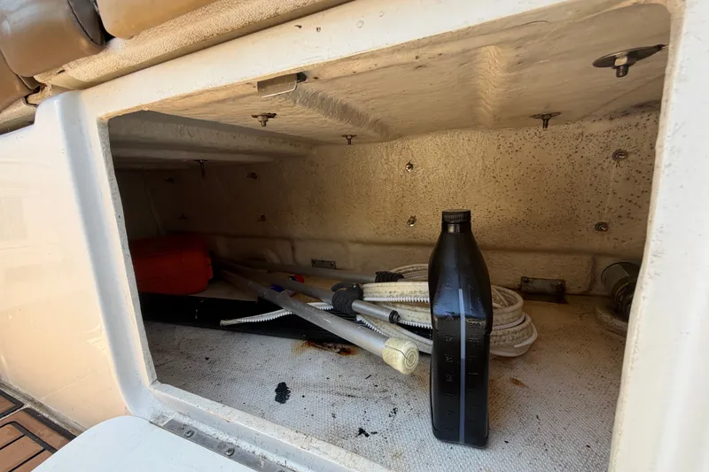 Slide: The Image of Storage compartment of a 2006 Sea Ray 300 Sundancer with boating equipment and a black bottle. - 107