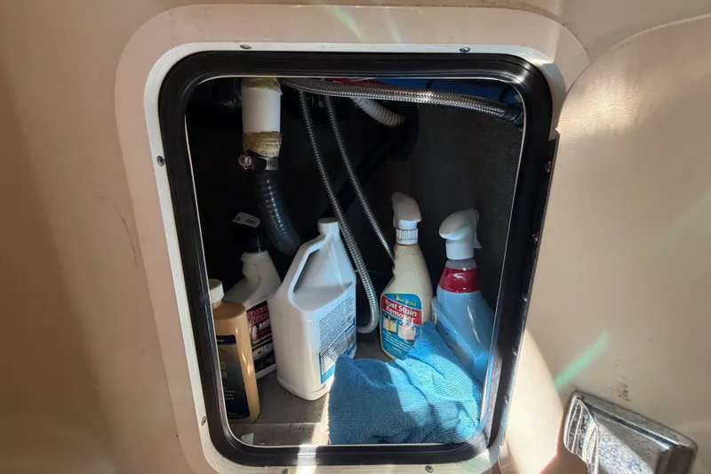 Slide: The Image of Storage compartment on a 2006 Sea Ray 300 Sundancer with cleaning supplies and a towel. - 64