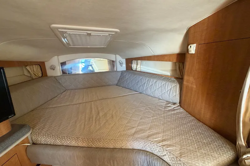 Slide: The Image of Interior cabin of 2006 Sea Ray 300 Sundancer with cozy bed and wooden accents. - 79