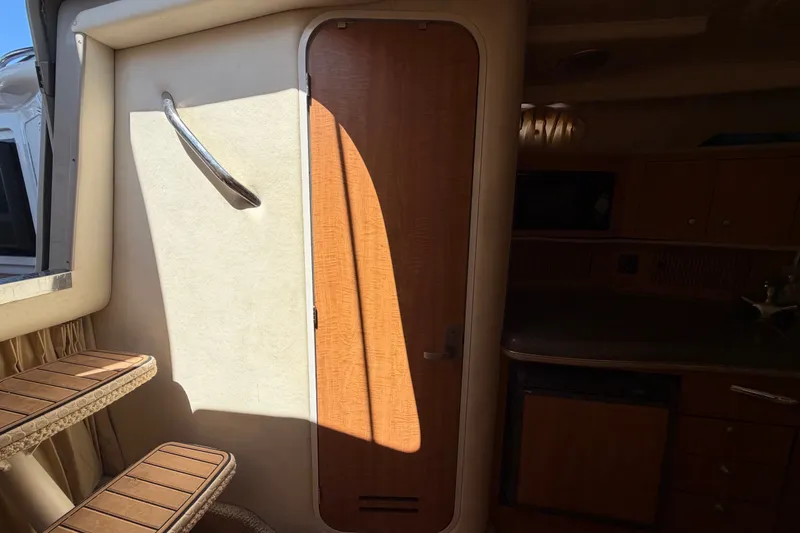 Slide: The Image of Interior of a 2006 Sea Ray 300 Sundancer, featuring wooden cabinetry and steps. - 57