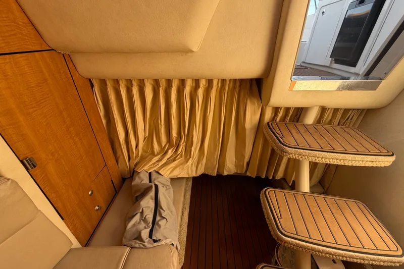 Slide: The Image of Interior of 2006 Sea Ray 300 Sundancer with wooden tables and beige curtains. - 92