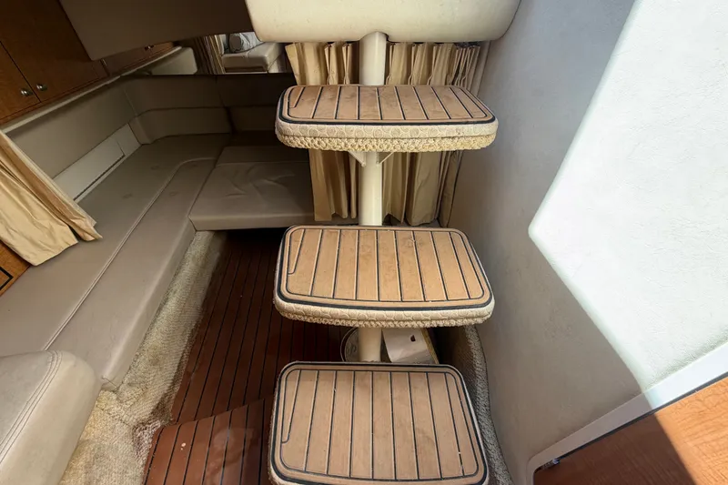 Slide: The Image of Interior of 2006 Sea Ray 300 Sundancer with wooden steps and beige seating. - 103