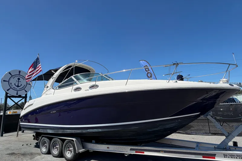 The Image of 2006 Sea Ray 300 Sundancer boat on trailer, displayed outdoors with American flag. - 0