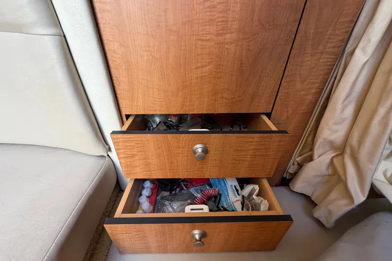 Slide: The Image of Wooden drawers with miscellaneous items inside a 2006 Sea Ray 300 Sundancer boat interior. - 96
