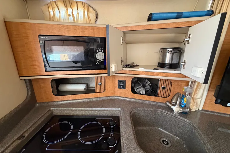 Slide: The Image of 2006 Sea Ray 300 Sundancer kitchen with microwave, stove, and sink. - 68