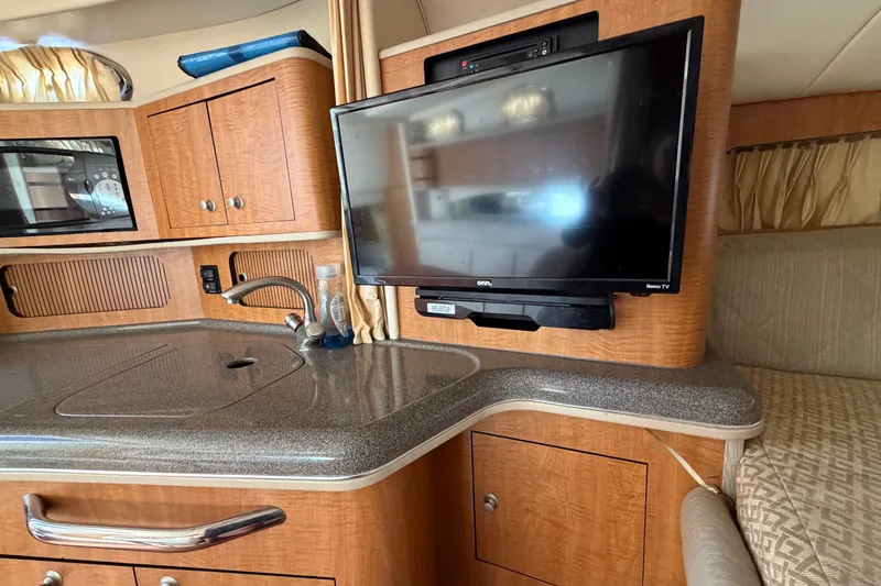 Slide: The Image of Interior of 2006 Sea Ray 300 Sundancer with TV, kitchenette, and wooden cabinetry. - 71