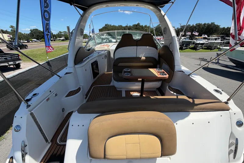 Slide: The Image of 2006 Sea Ray 300 Sundancer boat interior with seating and table, docked under clear skies. - 14