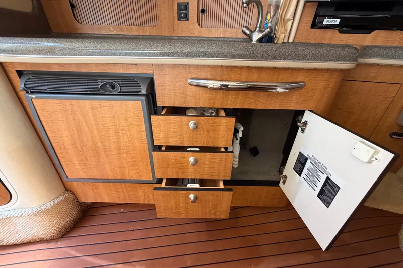Slide: The Image of 2006 Sea Ray 300 Sundancer interior kitchen with open drawers and cabinets. - 70