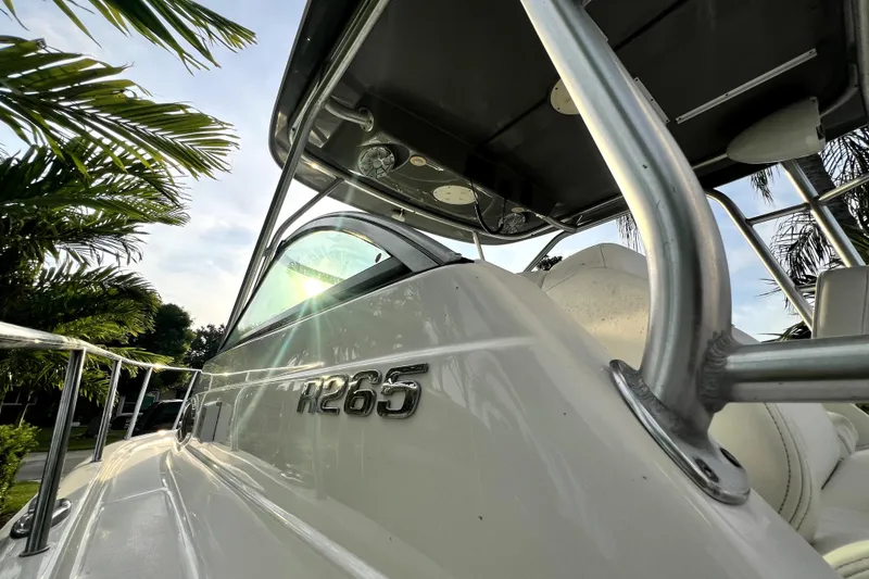 Slide: The Image of 2014 Robalo R265 Walkaround boat with sleek design, sunlight reflecting on hull. - 55