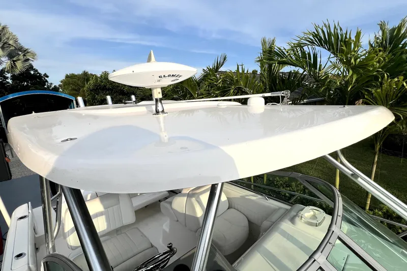 Slide: The Image of 2014 Robalo R265 Walkaround boat with radar, surrounded by lush greenery. - 90