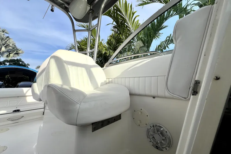 Slide: The Image of 2014 Robalo R265 Walkaround boat interior with white seating and speaker, surrounded by palm trees. - 114