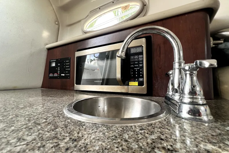 Slide: The Image of 2014 Robalo R265 Walkaround boat kitchen with sink, microwave, and control panel. - 127