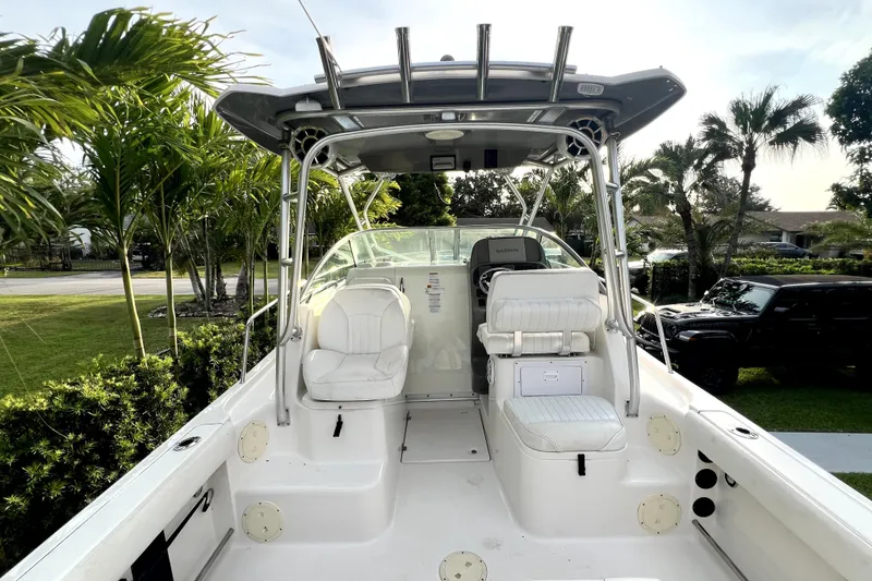 Slide: The Image of 2014 Robalo R265 Walkaround boat interior with seating and helm, surrounded by lush greenery. - 43