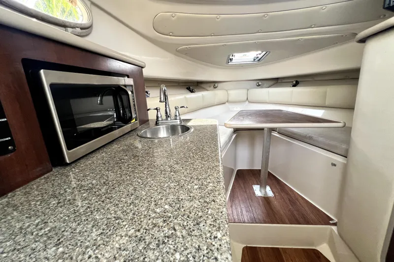Slide: The Image of 2014 Robalo R265 Walkaround cabin interior with kitchenette, sink, and seating area. - 73