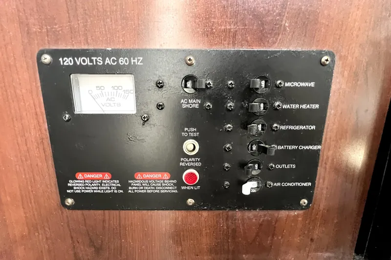 Slide: The Image of Electrical panel of a 2014 Robalo R265 Walkaround boat, featuring various switches and voltage meter. - 115