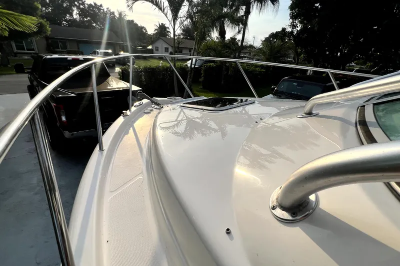 Slide: The Image of 2014 Robalo R265 Walkaround boat deck with railing, parked near vehicles and palm trees. - 91