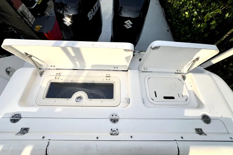 Slide: The Image of 2014 Robalo R265 Walkaround boat deck with open storage compartments and Suzuki engines. - 99