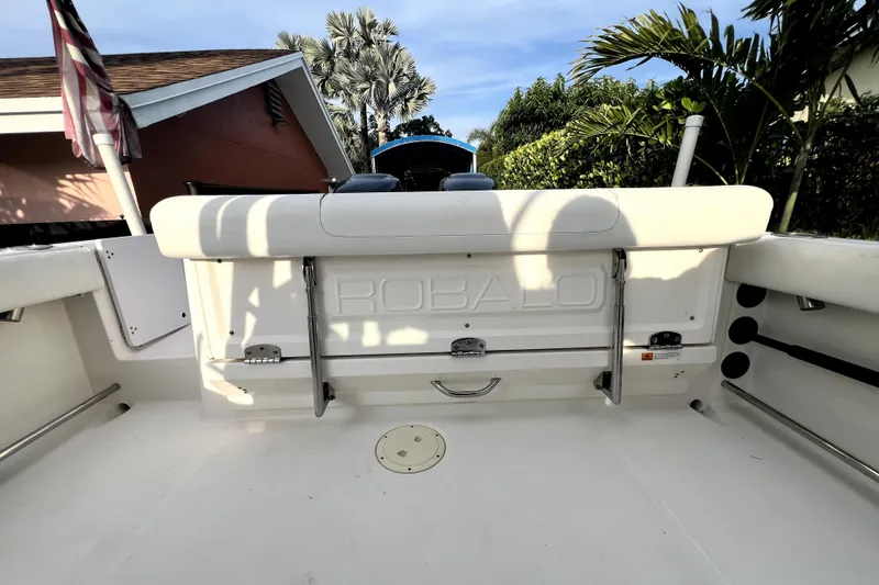 Slide: The Image of 2014 Robalo R265 Walkaround boat interior with seating and storage, surrounded by lush greenery. - 111