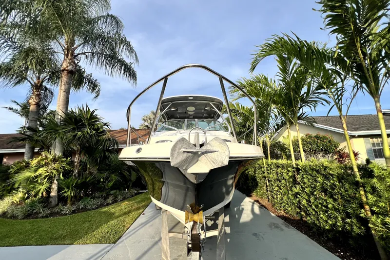 Slide: The Image of Een Robalo R265 Walkaround boot staat op een trailer in een tropische tuin. - 31