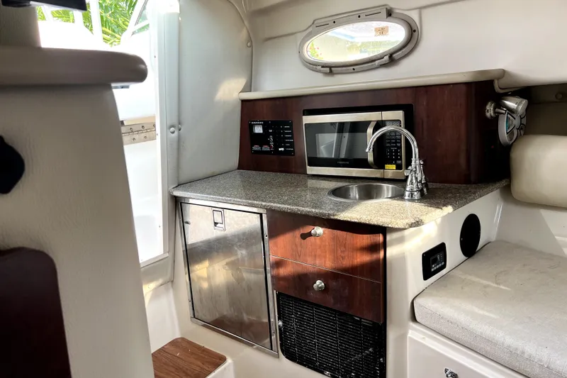 Slide: The Image of 2014 Robalo R265 Walkaround cabin with kitchenette, featuring microwave, sink, and storage. - 122