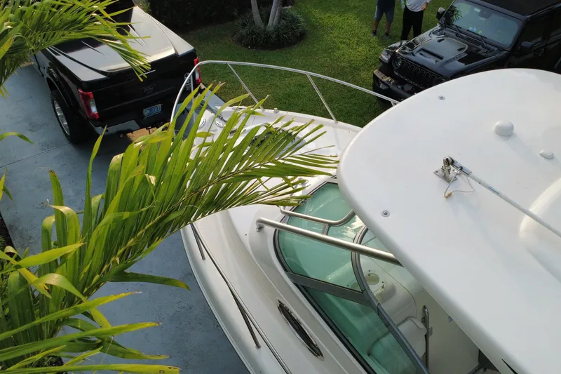 Slide: The Image of 2014 Robalo R265 Walkaround boat parked beside black vehicles, surrounded by greenery. - 23