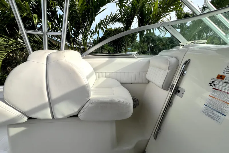 Slide: The Image of 2014 Robalo R265 Walkaround boat interior with white seating and lush greenery background. - 85