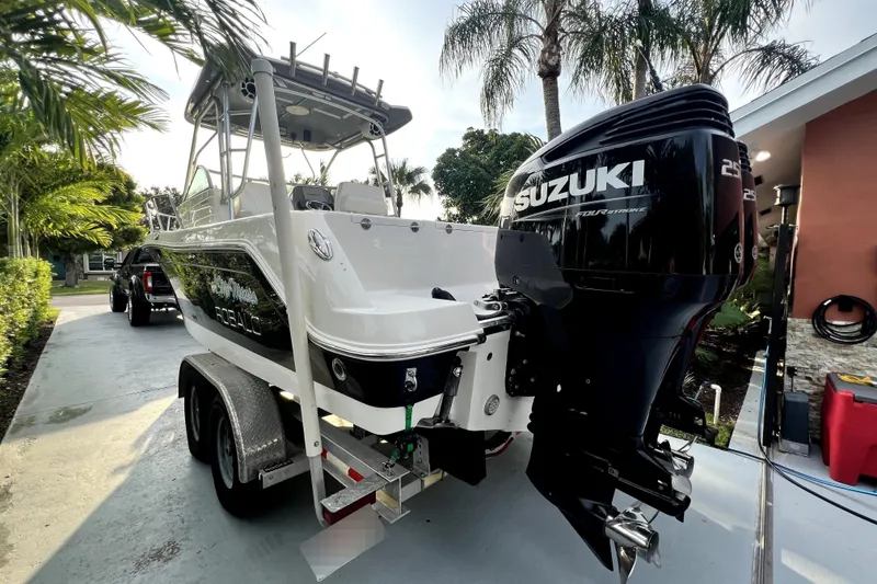 Slide: The Image of Un bateau Robalo R265 Walkaround de 2014 sur une remorque, entouré de palmiers. - 38