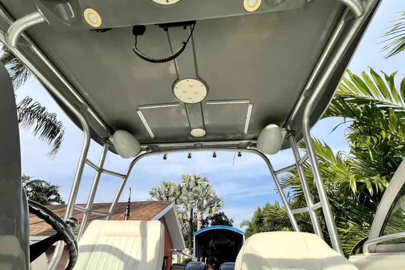 Slide: The Image of 2014 Robalo R265 Walkaround boat interior with canopy and seating, surrounded by tropical foliage. - 62