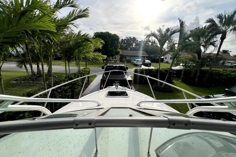 Slide: The Image of 2014 Robalo R265 Walkaround boat on trailer, surrounded by palm trees in a residential area. - 77