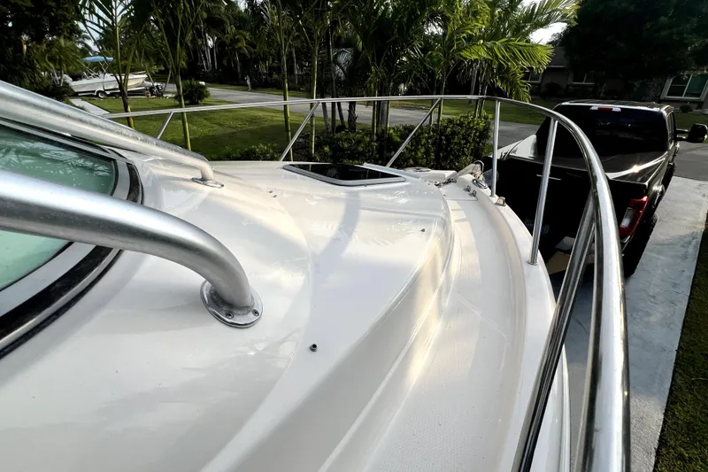 Slide: The Image of 2014 Robalo R265 Walkaround boat deck with railing, parked near a black truck. - 89