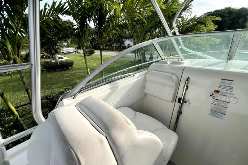 Slide: The Image of 2014 Robalo R265 Walkaround boat interior with white seating and lush greenery background. - 78