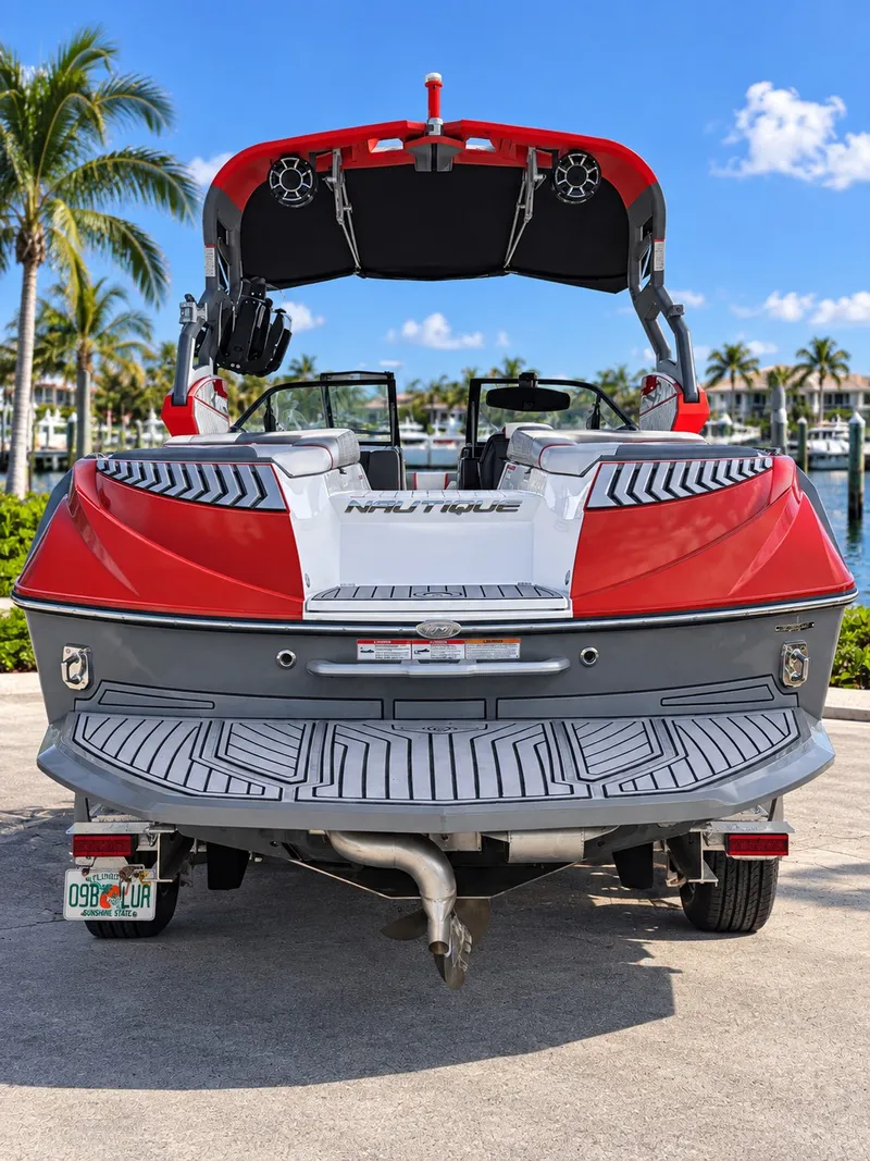 Slide: The Image of Red and gray sport boat with sleek design, parked on a trailer, surrounded by palm trees. - 2