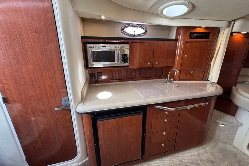 Slide: The Image of 2006 Sea Ray 340 Sundancer interior kitchen with wood cabinetry, microwave, and sink. - 64