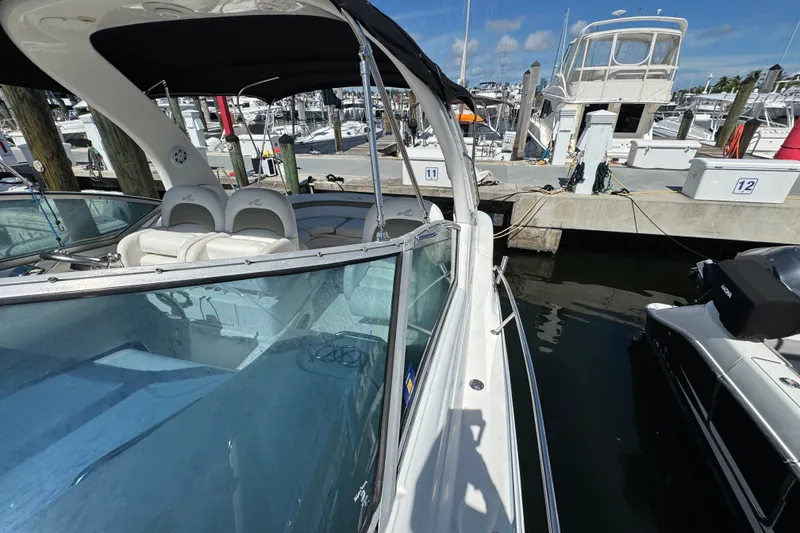 Slide: The Image of 2006 Sea Ray 340 Sundancer docked at marina, showcasing sleek design and spacious seating. - 58