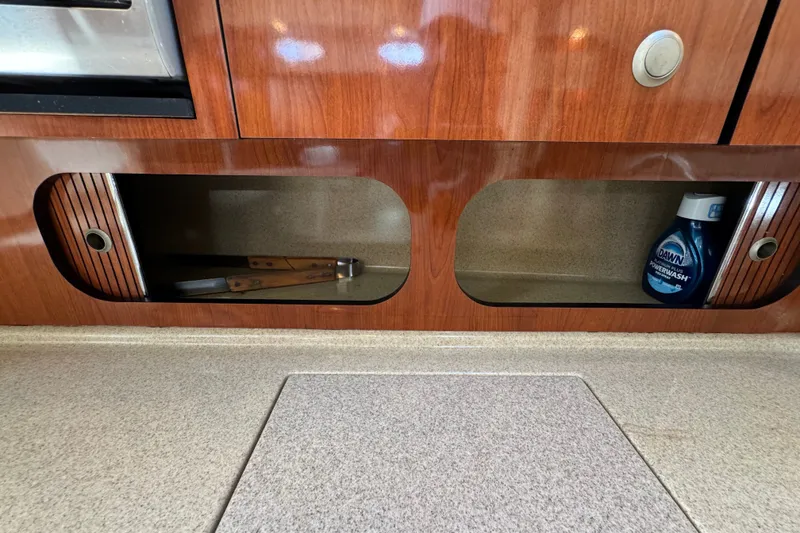 Slide: The Image of 2006 Sea Ray 340 Sundancer interior storage with wooden finish and cleaning supplies. - 88