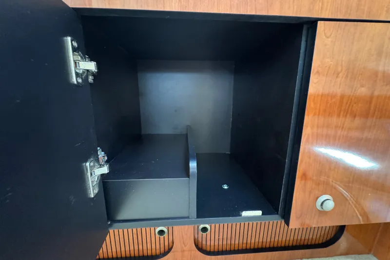Slide: The Image of Open cabinet inside a 2006 Sea Ray 340 Sundancer boat, featuring wooden finish and metal hinges. - 90