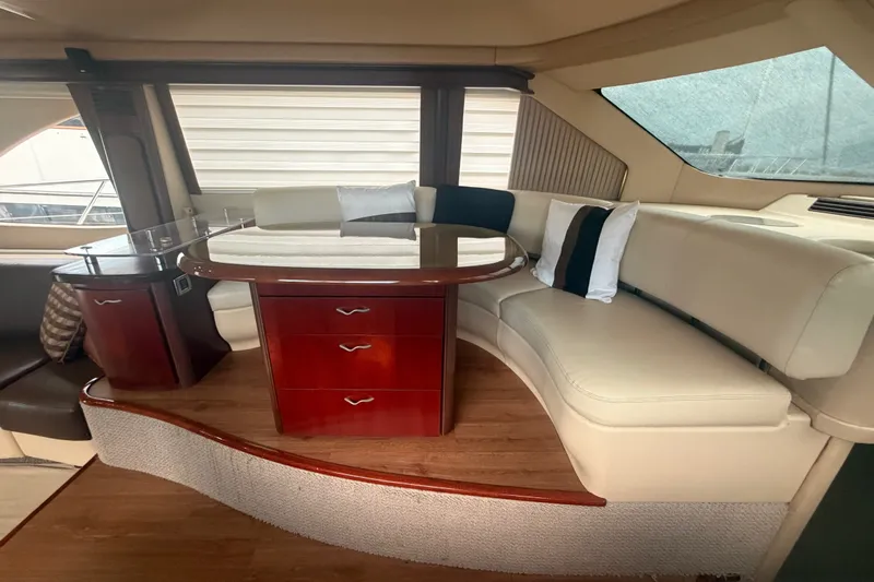 Slide: The Image of Luxurious interior of 2006 Sea Ray 550 Sedan Bridge with elegant seating and wooden table. - 68