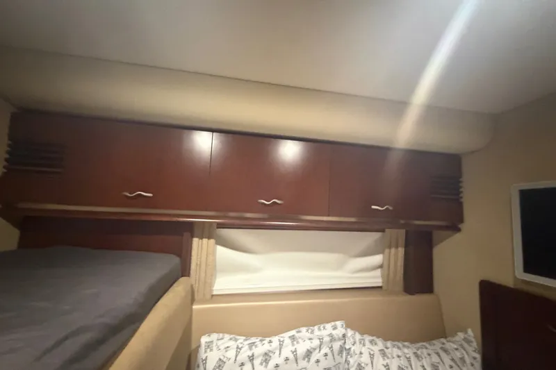 Slide: The Image of Interior cabin of 2006 Sea Ray 550 Sedan Bridge with wooden cabinets and bedding. - 99