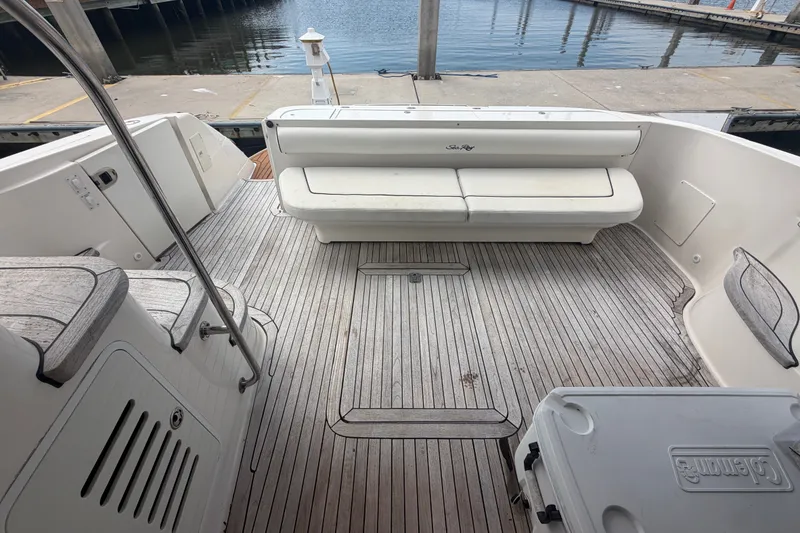 Slide: The Image of 2006 Sea Ray 550 Sedan Bridge yacht deck with seating and wooden flooring at a marina. - 45