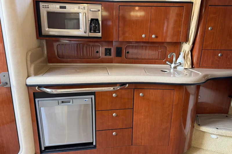 Slide: The Image of 2006 Sea Ray Sundancer 320 galley with microwave, sink, and wooden cabinetry. - 73