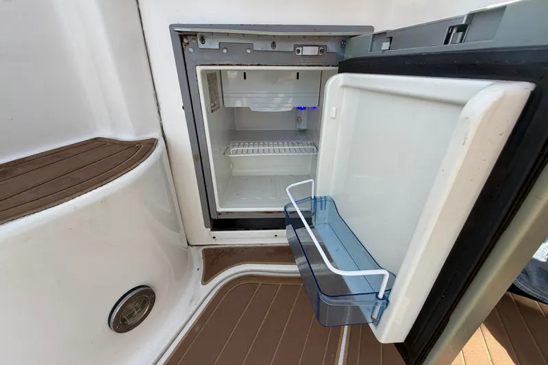 Slide: The Image of Open mini fridge on 2006 Sea Ray Sundancer 320 boat, showing interior shelves and door storage. - 54