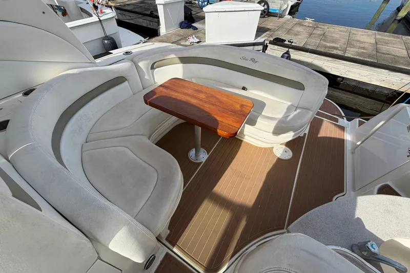 Slide: The Image of 2006 Sea Ray Sundancer 320 boat interior with cushioned seating and wooden table. - 52