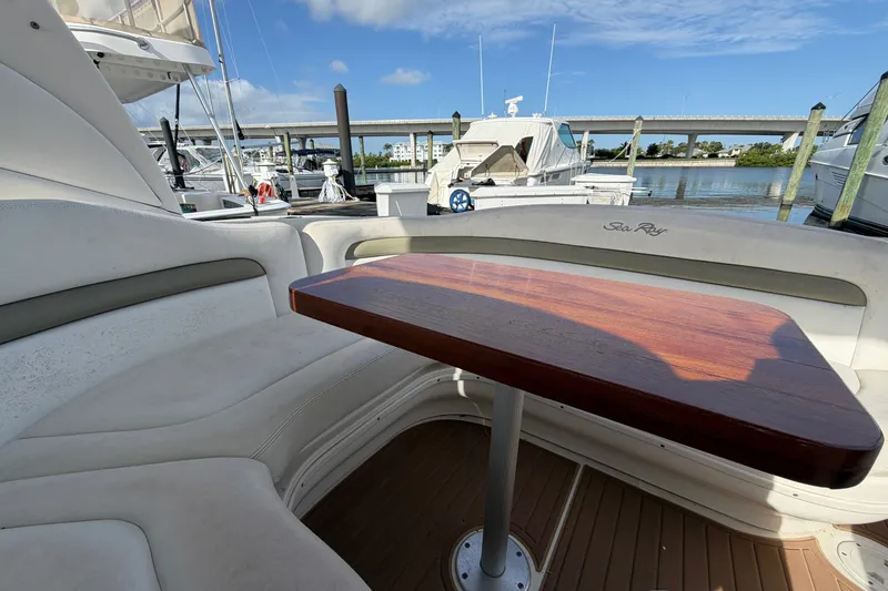Slide: The Image of 2006 Sea Ray Sundancer 320 interior with wooden table, docked at marina under blue sky. - 38