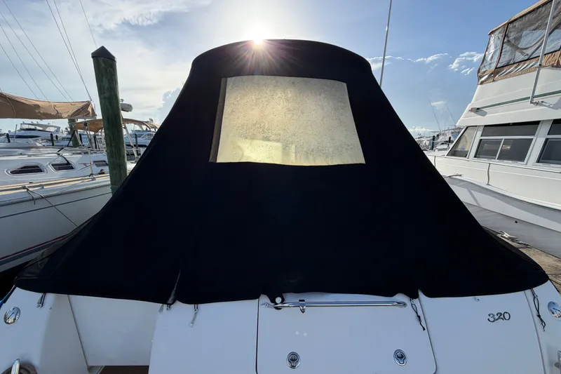 Slide: The Image of 2006 Sea Ray Sundancer 320 with black canvas cover at marina, sun shining above. - 15