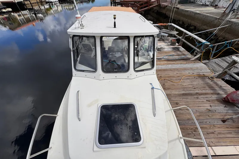 Slide: The Image of 2005 Atlas Boat Works Acadia 25 docked, showcasing cabin and deck details. - 6